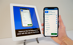 A smartphone with ID information held in front of a tablet kiosk.